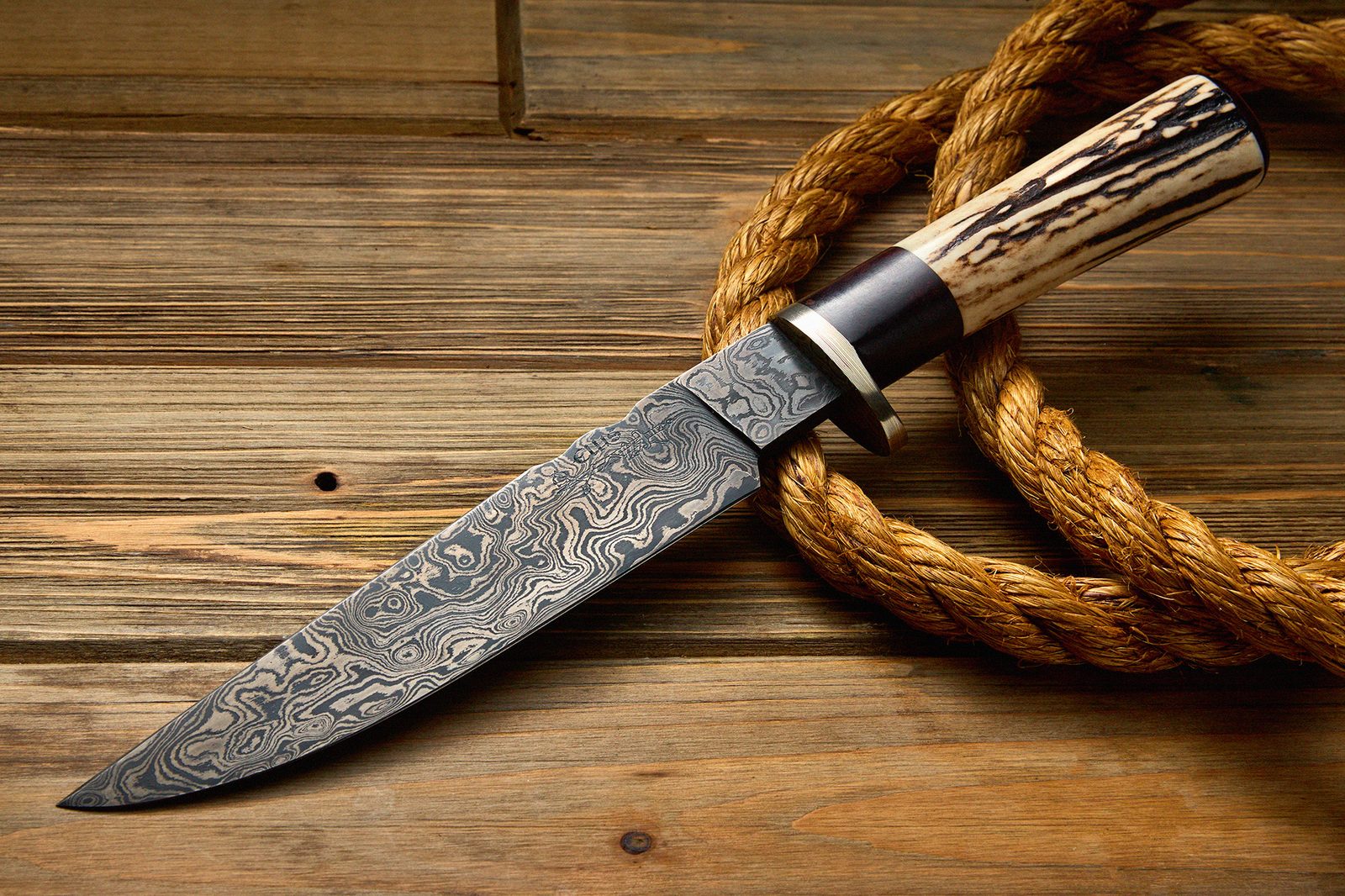 Damascus blade by ABS Mastersmith Dave Ellis photographed on wood and rope, back side